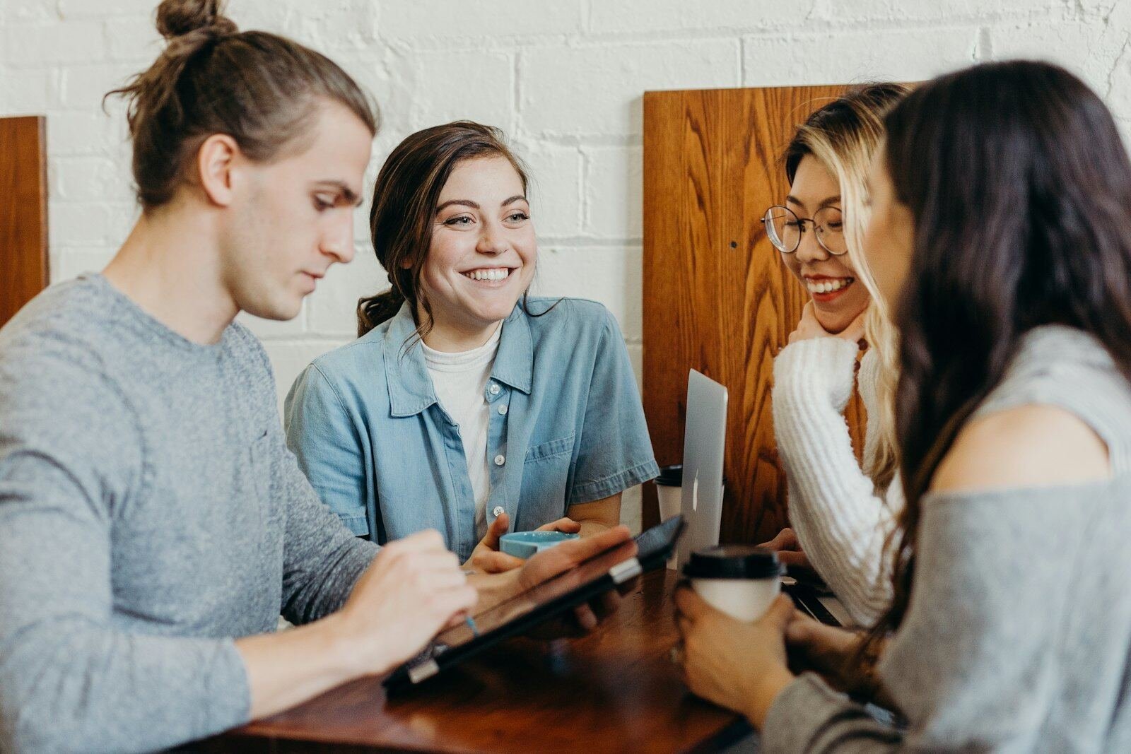 Friends smiling together over a tablet in a bright café