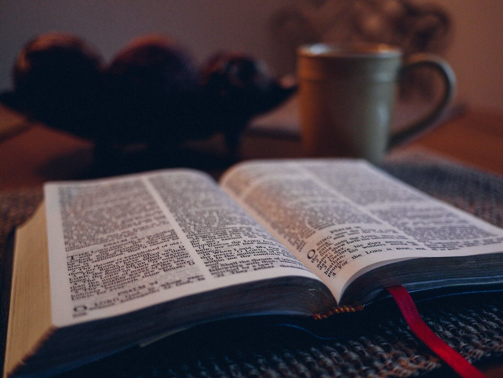 An open Bible beside a warm cup on a table