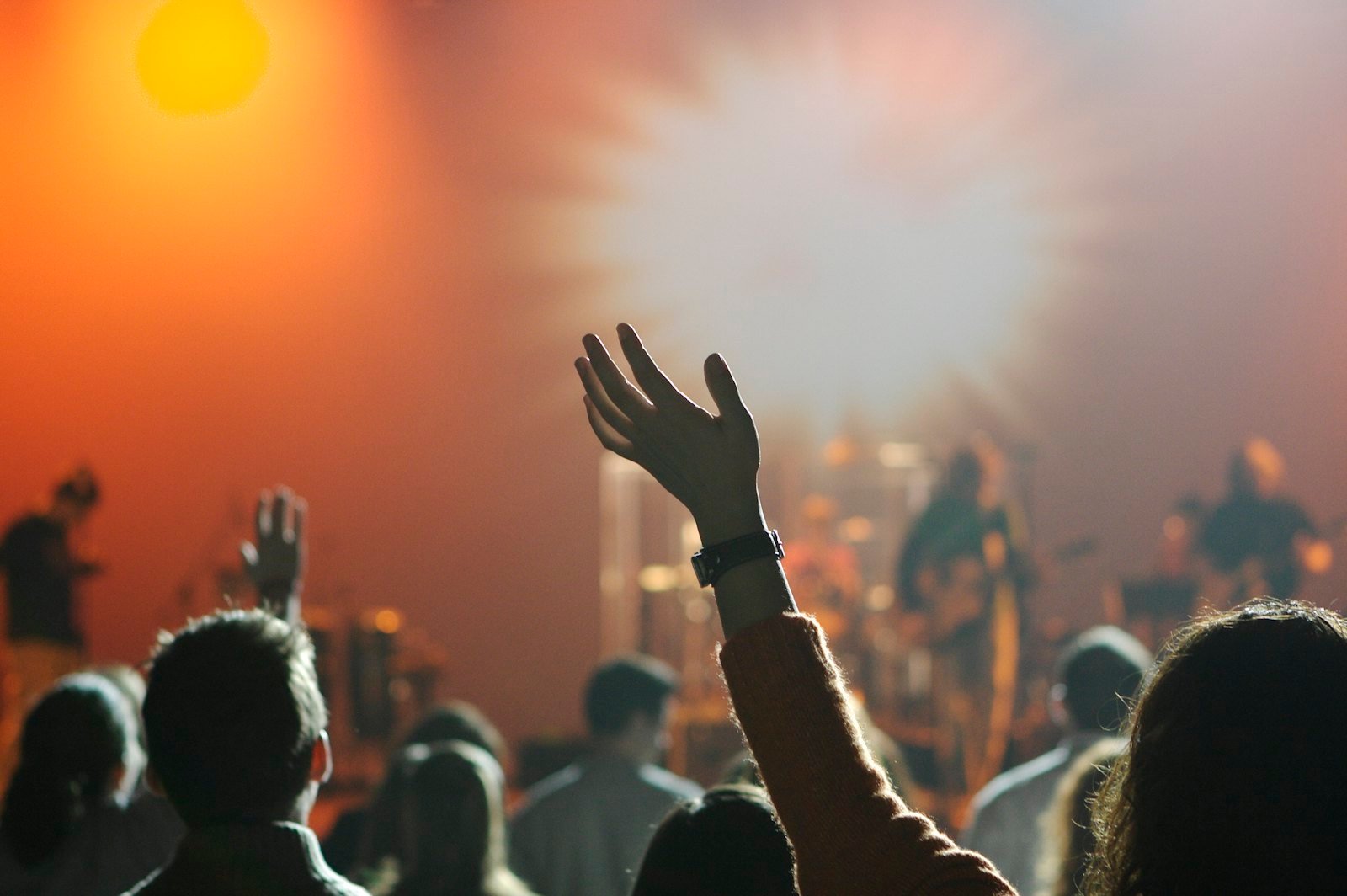 A worshipper raising a hand in a warmly lit church service