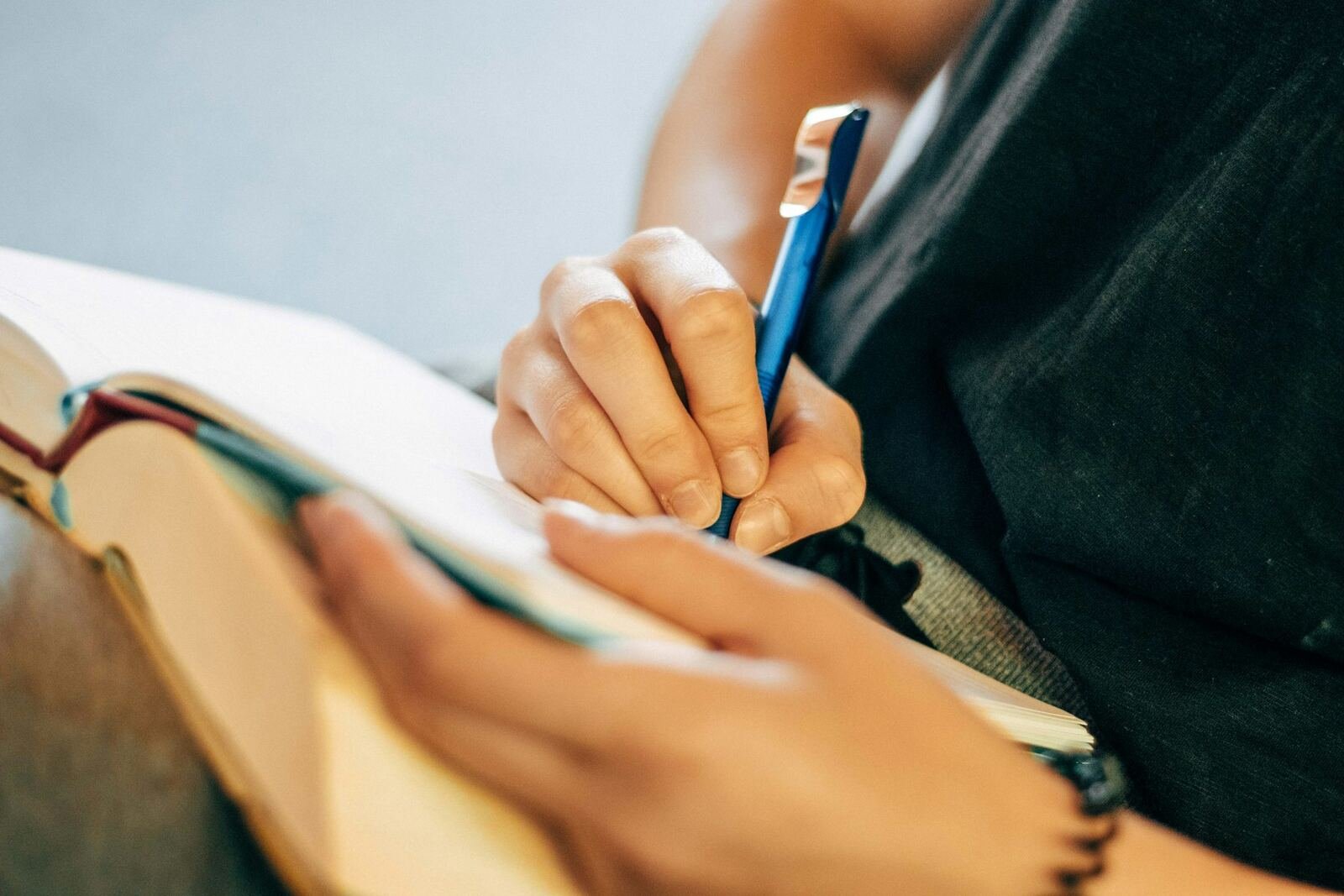 Close-up of a hand writing notes in a journal with a blue pen