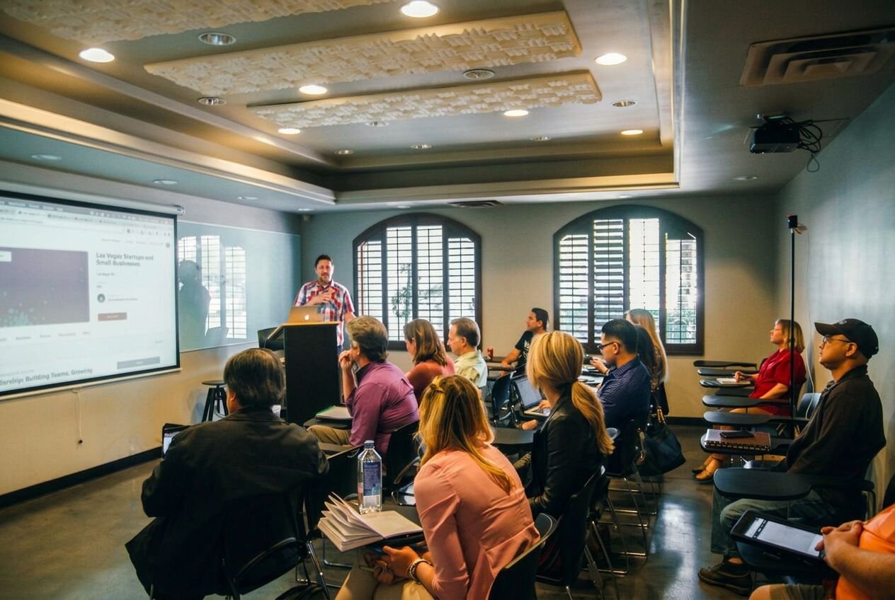 A presenter teaching a group in a classroom with a slide on the screen